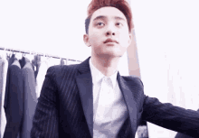 a young man in a suit and white shirt is standing in front of a closet .