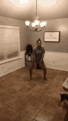 a woman is dancing in a room with a sign on the wall that says " love is always i 'm with you "