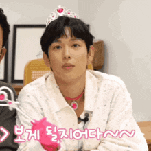 a man wearing a pink glove and a tiara with korean writing on the bottom