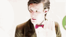 a man in a suit and bow tie is making a face .