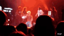 a blurry picture of a group of people standing on a stage in front of a crowd .
