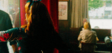 a woman with red hair is standing in a room with a sign that says tu on it