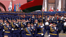 a group of soldiers marching in a parade with a flag in the middle