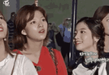 a group of young women are standing next to each other and looking at each other .