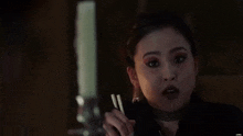 a woman is holding chopsticks in her hand and making a face .