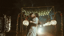 a man and woman are dancing under a canopy with lights