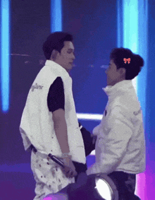two men standing next to each other with one wearing a white vest that says supreme