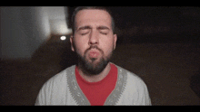 a man with a beard is blowing a kiss at the camera