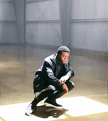 a man squatting down in a room with a striped wall