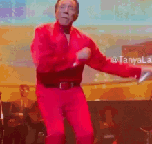 a man in a red shirt is dancing on a stage .