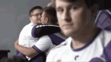 a group of men are hugging each other while wearing purple and white jerseys .