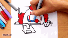 a person is drawing a clown with a red nose on a piece of paper that says drawbook