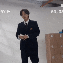 a man in a suit and tie is standing in front of a wooden locker with a play button in the background