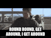 a man is standing in front of a truck and says round round , get around , i get around .