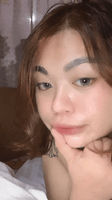 a woman with a tattoo on her arm holds her hand to her chin