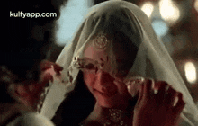 a woman in a white veil is crying while being held by a man .