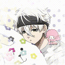 a boy with white hair and a headband is laying next to a stuffed animal with flowers on it