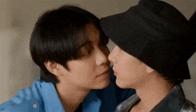 two men in hats are kissing each other 's noses .