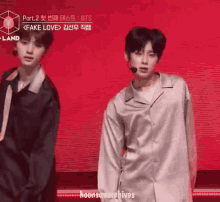 two young men are standing next to each other on a stage and one of them is wearing a shirt that says fake love