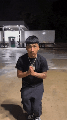 a man is kneeling down with his hands folded in front of a white truck that says d & g on it