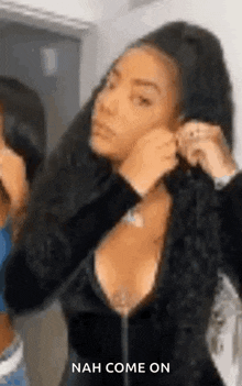a woman is putting on earrings in front of a mirror while wearing a black dress .