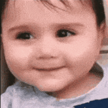 a baby is smiling for the camera and looking at the camera .