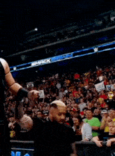 a man in a black vest is standing in front of a crowd in a stadium .
