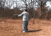 a man is standing in a field with a shotgun in his hand .