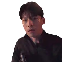 a man in a black shirt is holding a gun and looking at the camera