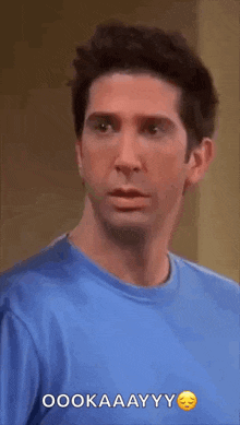a man in a blue shirt is making a funny face and says oookaaayyy .