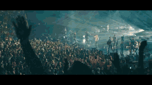 a crowd at a concert with their hands up in the air