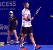 a man is holding a tennis racquet in front of a sign that says ' ess '
