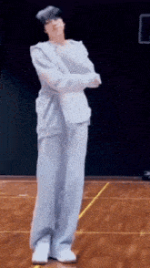 a man in a white suit is dancing on a wooden floor