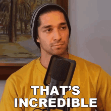 a man in a yellow shirt stands in front of a microphone and says " that 's incredible "