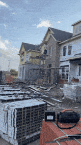 a man stands on a scaffolding in front of a house that is being built and a stack of bricks