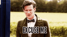a man in a suit and bow tie is standing in a field and says excuse me .