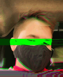 a young man wearing a black face mask with a green stripe across his eyes