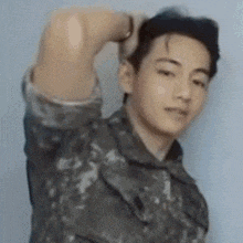 a man in a military uniform is standing with his arm over his head .
