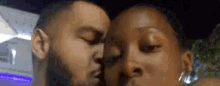 a man and a woman are kissing each other in a close up of their faces .