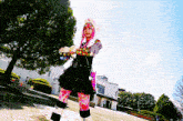a woman with pink hair is standing in front of a large building