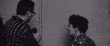 a black and white photo of a man and a woman standing next to each other .
