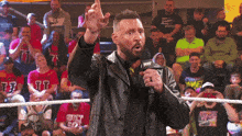 a man in a leather jacket is talking into a microphone with the word next on it