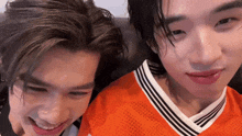 two young men are sitting next to each other on a couch and smiling