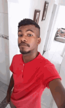 a man in a red shirt is taking a picture of himself