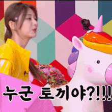 a woman in a yellow raincoat is standing next to a unicorn statue