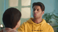 a man wearing a yellow hoodie that says by myself