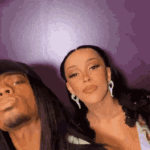 a man and a woman are posing for a picture together against a purple wall .