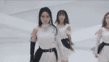 a woman in a white dress with a black belt is dancing