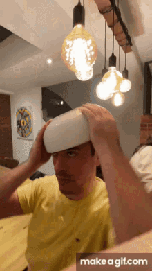 a man in a yellow shirt is holding a white bowl over his head