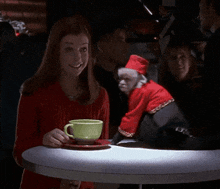 a woman sitting at a table with a monkey wearing a santa outfit
